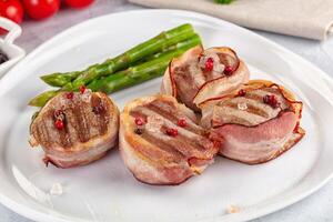 Three pieces of bacon wrapped in asparagus on a white plate photo