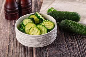 A bowl of cucumbers and a bottle of vinegar photo