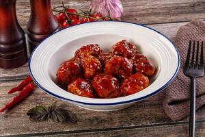 A bowl of meatballs with sauce and a fork photo
