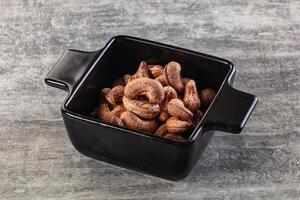 Cashews in a black square bowl on a gray background photo