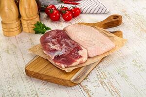 Two raw meat pieces on a cutting board with a knife and a wooden cutting board photo