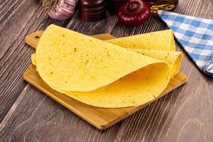 A tortilla on a cutting board next to a bottle of olive oil photo