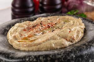 A bowl of hummus with a side of garlic photo