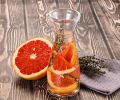 A glass pitcher with grapefruit slices and herbs photo