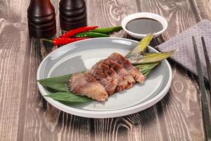 A plate of food on a table with chopsticks and a bottle of sauce photo
