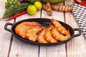 A pan of shrimp on a table with vegetables and other food photo