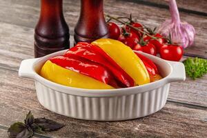 A bowl filled with peppers and tomatoes on a table photo