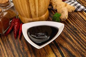 A wooden table with a bowl of sauce, spices and ginger photo