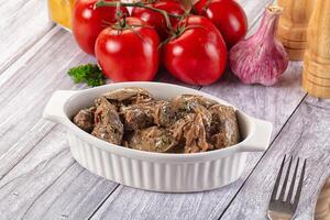 A bowl of meat with vegetables on a table photo