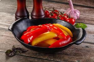 A bowl of peppers and onions sitting on a table photo