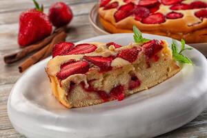 A slice of cake on a plate next to a bowl of strawberries photo