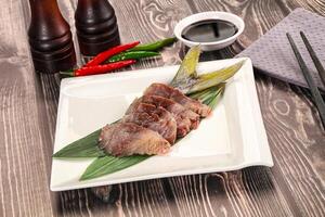 A plate with a piece of meat on it and some chopsticks photo