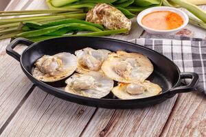 A pan with scallops and vegetables on a table photo