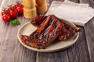 Two ribs on a plate with a napkin and a bottle of sauce photo