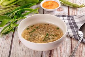 A bowl of soup with a spoon and some celery photo