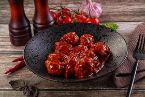 A bowl of meatballs with sauce on a wooden table photo