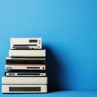 Stack of retro electronics against a blue wall photo