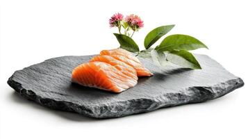 Fresh salmon sashimi slices on dark stone plate, garnished with flowers and leaves photo