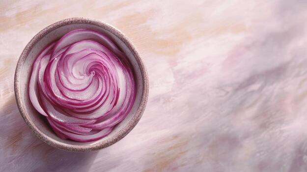 Thinly sliced red onion rings arranged in a spiral pattern in a light-colored bowl, resting on a pale, textured surface photo