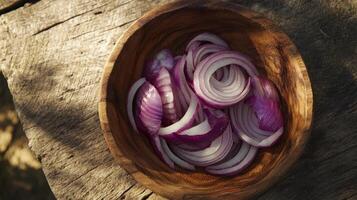 Thinly sliced red onions in a wooden bowl on a rustic wooden surface photo