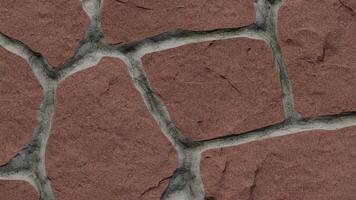 Close up shot of a red stone wall with grey mortar filling the gaps in between the stones photo