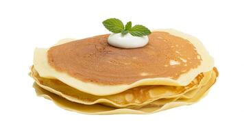 Stack of pancakes topped with cream and mint leaves on a white background, isolated view photo
