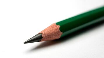 A close up shot of a green pencil with a sharpened tip on a white surface in soft lighting photo