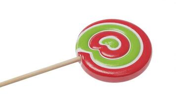 Close up of a red and green swirled lollipop with a wooden stick on a white background photo