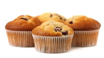 A group of four muffins with white paper liners on a white surface in a studio setting shot photo