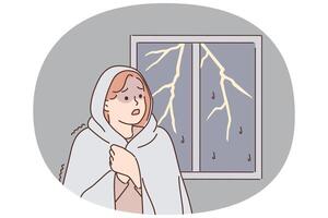 Woman was frightened by lightning and storm outside window wrapped herself in blanket vector