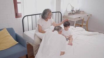 In a bright and inviting bedroom, grandparents interact with their young grandchild, fostering love and connection while spending quality time together. The atmosphere is warm and nurturing. video