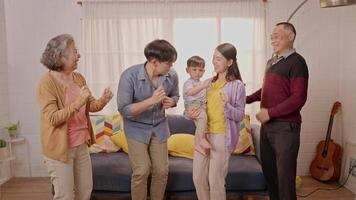 A family is gathered in their warm living room, dancing happily together. The cheerful atmosphere includes a young child in the mix, adding to the fun and excitement of the moment. video