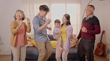 In a warm, inviting living room, a family enjoys an afternoon of laughter and dance. They share smiles as they dance together, creating cherished memories. video