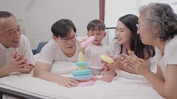 A joyful family engages in playful activities with a young child, who is focused on stacking colorful rings. Laughter and smiles fill the cozy indoor space. video