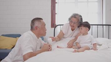Grandparents engage with their young grandson in a warm, inviting room filled with natural light, fostering connection and joy as they play together. video