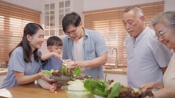 In a cozy kitchen, a family joyfully prepares a fresh salad. They chop vegetables, share smiles, and create a warm atmosphere, showcasing the importance of togetherness during mealtime preparation. video