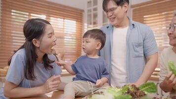 A family gathers in their bright kitchen, engaging in a cooking session with fresh vegetables. Laughter fills the air as they playfully interact and share moments of joy together. video