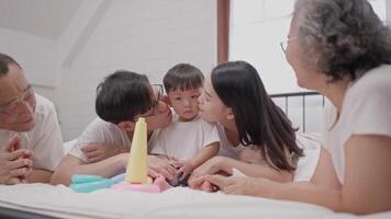 A joyful gathering family members in a bright, warm room, spending precious moments together while engaging a young child with toys, laughter, and affection. video
