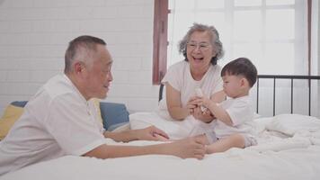 A joyful interaction unfolds as grandparents engage with their curious toddler in a bright, comfortable room. Laughter and playful gestures create warm memories during a sunny morning. video