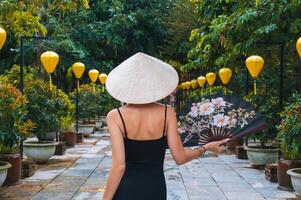 A woman, in a traditional Vietnamese hat on the background of an Asian cultural garden decorated with lanterns photo