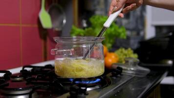 cook pasta close-up dry spaghetti pasta noodles being cooked in boiling water within transparent glass pot on a stove, creating a visually appealing contrast between the pasta and bubbling water video
