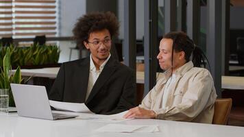 Two multiracial business men African American businessmen partners diverse colleagues males discuss online internet data analyzing marketing project result using laptop talk at office desk cooperation photo