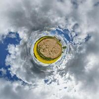 A small planet with clouds and a field of yellow flowers photo