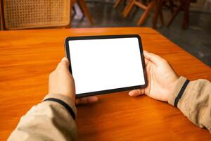 Man using a tablet with a blank screen, placed on a wooden table with a stylus photo