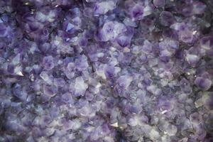 Close-up of natural amethyst crystals with shimmering purple hues, creating a textured abstract background perfect for use as copy space in design. photo