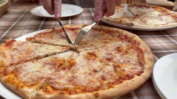 Man takes a slice of pizza with a knife and fork. Pizzeria. Italian cuisine. Pizza Margherita. video