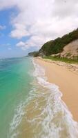 Cinematic FPV drone shot gliding along Pandawa Beach in Bali, Indonesia. Crystal-clear turquoise water, golden sand, and tropical cliffs in summer light. Ideal for travel and nature themes. video