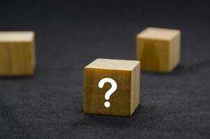 Three wooden cubes with question marks aligned in a row photo