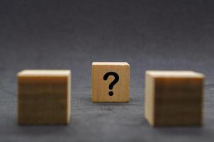 Two dark wooden cubes with question marks on a black background photo