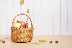 Autumn harvest basket with apples, zucchini and peppers on a wooden background. photo